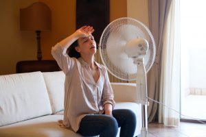 woman-sitting-on-couch-in-front-of-fan-looking-very-hot