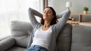 woman-leaning-back-on-couch-with-eyes-closed-and-smiling